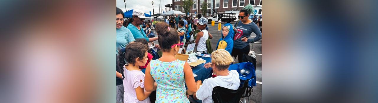 Children and parents gathered around the Alliance table at a community Ice Cream Social sponsored by Assemblywoman Yvonne Lopez.