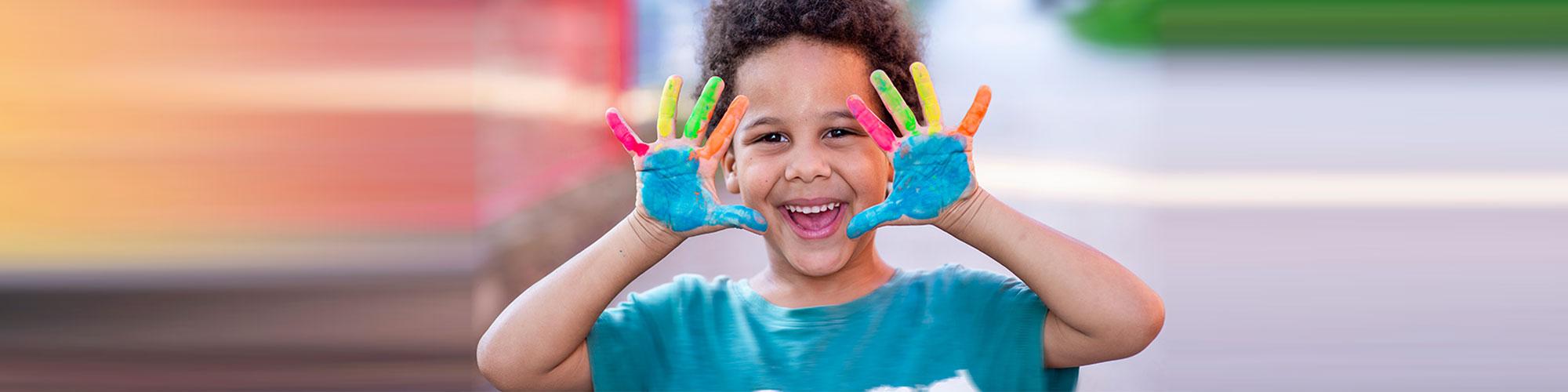 little boy happy with paint on his hands 